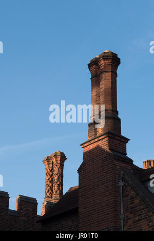 Dettaglio di camini e parapetto lungo la parte superiore di un edificio Tudor parete esterna con windows e ornamenti Foto Stock