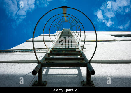 Fire escape scala di metallo su un edificio industriale con cielo blu Foto Stock