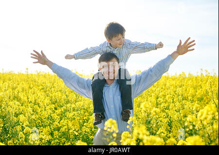 Padre contiene un piccolo figlio sulle sue spalle Foto Stock