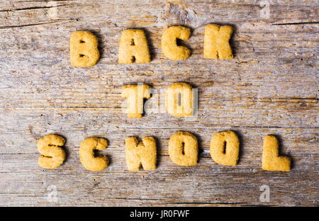 Si torna a scuola scritto con i cookie su un tavolo di legno Foto Stock