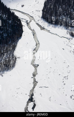 Vista aerea di un fiume che scorre attraverso la neve nel Kenai Mountains In inverno, Kachemak Bay State Park; Alaska, Stati Uniti d'America Foto Stock