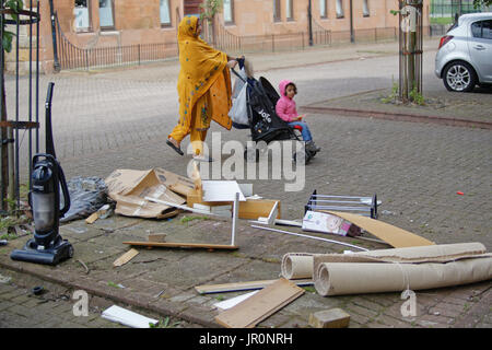 Govanhill Glasgow famiglia asiatica rifugiato vestito Hijab sciarpa su strada nel Regno Unito scena quotidiana il trasporto delle borse della spesa Foto Stock