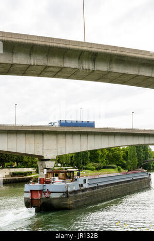 Un vuoto che la bettolina scendendo lungo il corso del fiume Marne verso Parigi mentre un semi-rimorchio il carrello procede su una rampa della A86 autostrada su vie navigabili. Foto Stock