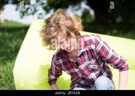 Ragazza seduta su un gonfiabile all'aperto Foto Stock