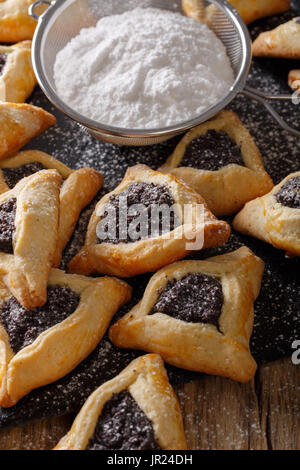 Hamantaschen cookie con un riempimento di papavero per celebrare la festa di Purim close-up su una tavola verticale. Foto Stock