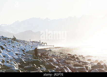 Surfer su una spiaggia rocciosa lungo Kachemak Bay, Homer Spit, Penisola di Kenai, centromeridionale Alaska, STATI UNITI D'AMERICA Foto Stock