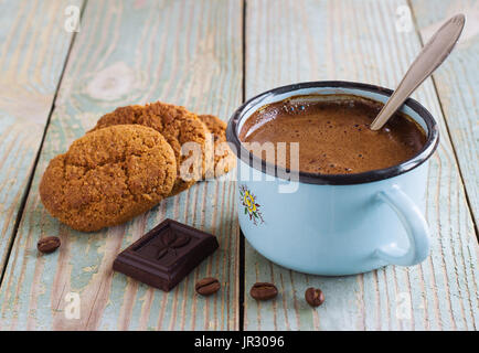 Un caffè in una tazza di metallo sul vecchio blu sullo sfondo di legno con grani di avena cookie Foto Stock