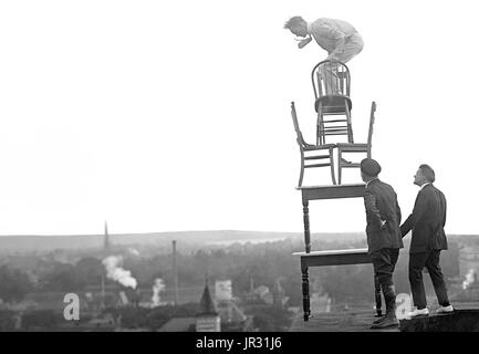 La Reynolds eseguendo acrobazie e bilanciamento del carico agisce sul alto cornicione al di sopra di 9 street N.W. Washington, DC. Giovanni "Jammie' Reynolds (nato 1890 o 91 - ?) era un americano il temerario. Poco è noto circa i primi anni di vita, che cosa è stato di lui una volta che ha smesso di eseguire o anche il suo vero nome. Un acrobata e giocoliere, egli è conosciuto da molti nomi - Daredevil Johnny, Daredevil Jack, la meraviglia di arrampicata, la lucertola, l'Uomo ragno, e il volo umano. Un articolo di giornale da 1922 precedenti ha iniziato ad esibirsi all'età di sei anni in Buffalo, in equilibrio su un piede da un pennone 140 piedi in aria. Il suo primo grande stunt Foto Stock