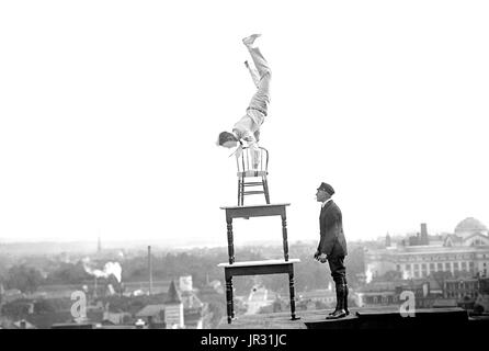 La Reynolds eseguendo acrobazie e bilanciamento del carico agisce sul alto cornicione al di sopra di 9 street N.W. Washington, DC. Giovanni "Jammie' Reynolds (nato 1890 o 91 - ?) era un americano il temerario. Poco è noto circa i primi anni di vita, che cosa è stato di lui una volta che ha smesso di eseguire o anche il suo vero nome. Un acrobata e giocoliere, egli è conosciuto da molti nomi - Daredevil Johnny, Daredevil Jack, la meraviglia di arrampicata, la lucertola, l'Uomo ragno, e il volo umano. Un articolo di giornale da 1922 precedenti ha iniziato ad esibirsi all'età di sei anni in Buffalo, in equilibrio su un piede da un pennone 140 piedi in aria. Il suo primo grande stunt Foto Stock