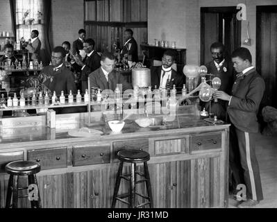 Laboratorio di Chimica/classe con studenti presso l istituto di Tuskegee, Tuskegee, Alabama. George Washington Carver si erge secondo da destra, rivolto verso la parte anteriore (incorniciato dalla porta). George Washington Carver (1864 - Gennaio 5, 1943) era un afro-americano di scienziato, botanico, educatore e inventore nato in schiavitù. Nel 1891 ha frequentato e studiato botanica alla Iowa State Agricultural College dove egli fu il primo studente nero e in seguito ha insegnato come il primo nero membro della facoltà. La sua reputazione si basa sulla sua ricerca e promozione di colture alternative per il cotone, come arachidi, semi di soia e sw Foto Stock