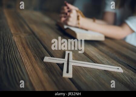 Giovani pregando womans mani con il rosario in legno e la Sacra Bibbia. Concetto di religione Foto Stock