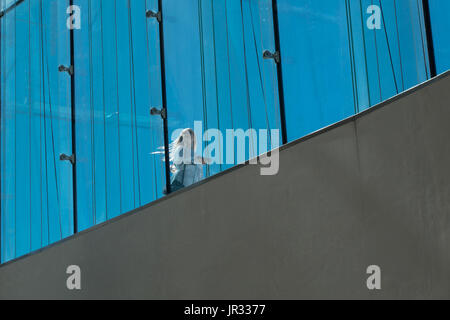 Oslo, Norvegia - 21 Maggio 2017 - bionda donna caucasica con valige a rullo sulla piattaforma di visualizzazione di Oslo opera house sulla giornata di vento soffia capelli intorno Foto Stock