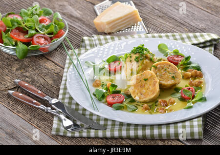 Alto Adige gnocchi di pane con formaggio grigio, serviti con burro e noci, parmigiano reggiano in background Foto Stock