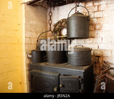 In vecchio stile di cucina in legno con stufa di ghisa pentole contro un muro di mattoni Foto Stock