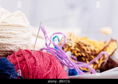 Colorata lana palle e aghi in cesto di legno. Lana per maglieria Foto Stock