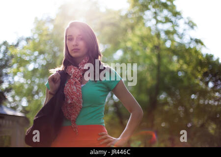 Bella giovane donna con eco-friendly tessuto borse per lo shopping. La luce solare naturale e flare ottico con alberi in background. Foto Stock