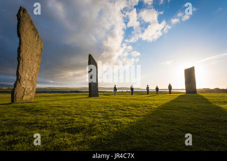 Un gruppo di turisti si presentano come le pietre a Standing Pietre di Stenness, Orkney sito neolitico Foto Stock