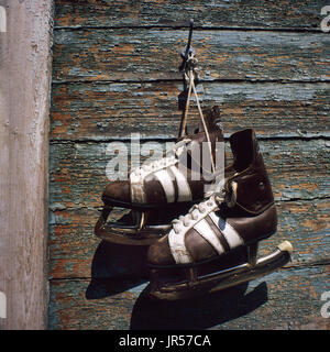 Vintage coppia di mens pattini da ghiaccio appeso a una parete in legno Foto Stock