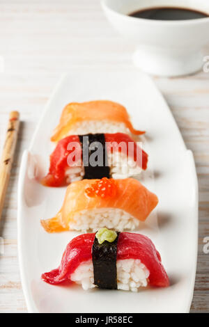 Set di salmone e tonno rosso Nigiris sulla piastra bianca sopra il vecchio legno bianco. Pesce crudo nel sushi tradizionale Giapponese di stile. L'immagine verticale. Foto Stock