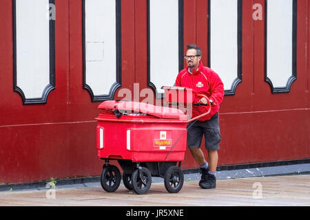 Royal mail Postman con grande buggy con ruote per pacchi pieni, che consegna la posta nel centro di Preston, Regno Unito Foto Stock