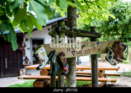 Etichetta di partito stivali di gomma segno della foresta di legno tree house Herzlich Willkommen significa Benvenuti Foto Stock