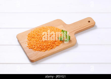 Pila di pelati di lenticchie rosse sul bianco sullo sfondo di legno Foto Stock