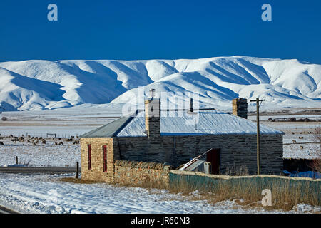 Storico cottage in pietra e gamma di Ida in inverno, Colline Creek, Maniototo di Central Otago, Isola del Sud, Nuova Zelanda Foto Stock