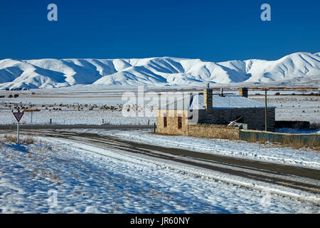 Storico cottage in pietra e gamma di Ida in inverno, Colline Creek, Maniototo di Central Otago, Isola del Sud, Nuova Zelanda Foto Stock