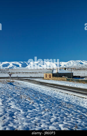 Storico cottage in pietra e gamma di Ida in inverno, Colline Creek, Maniototo di Central Otago, Isola del Sud, Nuova Zelanda Foto Stock