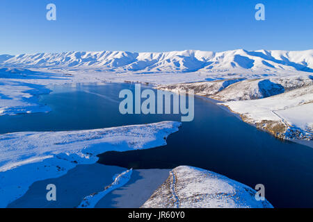 Ghiaccio in corrispondenza del bordo della Falls Dam e Gamma Hawkdun in inverno, Maniototo di Central Otago, South Island, in Nuova Zelanda - antenna fuco Foto Stock