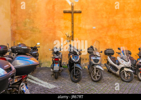 Roman scooter parcheggiati in un cantiere con una croce sulla parete posteriore, Foto Stock