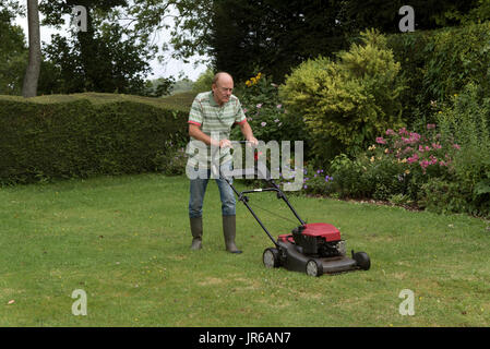 Uomo che utilizza un tagliaerba rotativa di tagliare la sua erba Foto Stock