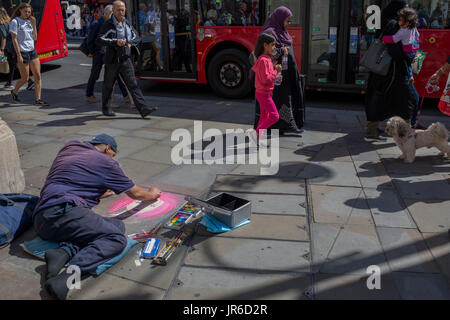 L'artista di strada Nick C rende un pastello ritratto di una ragazza in rosa, per gli acquirenti e i pedoni, il 31 luglio 2017, in Oxford Street a Londra, Inghilterra. Foto Stock