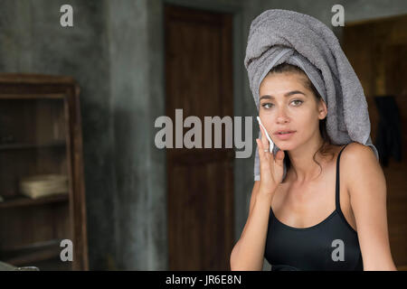 Donna con un asciugamano sulla testa di ascoltare la rimozione di make-up Foto Stock