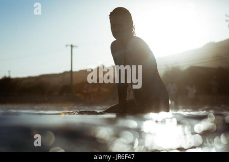 Silhouette di una donna seduta su una tavola da surf, Malibu, California, America, STATI UNITI D'AMERICA Foto Stock