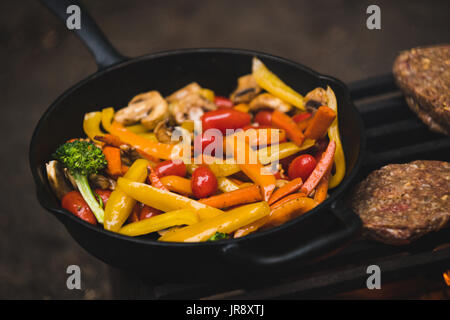 Hamburger e verdure per la cottura su un barbecue Foto Stock