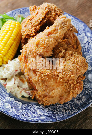 Il siero di latte fritto di pollo con mais e insalata di patate su una piastra di colore blu Foto Stock