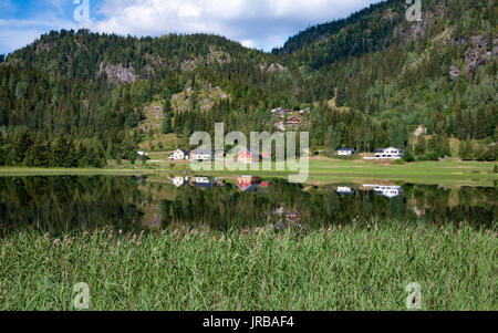 Case in valle riflettendo in acqua costruita sulla sponda di un fiordo, Telemark, Norvegia Foto Stock