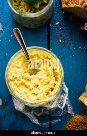 Vista superiore del pollo al curry crema servita su un pane bruschetta con ingredienti su un blu sfondo arrugginito Foto Stock