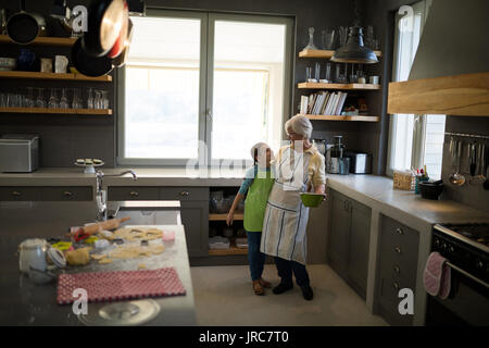 Nonna sorridente e nipote abbracciando in cucina Foto Stock