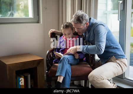 Concentrato di padre e figlia la lettura di un libro a casa Foto Stock