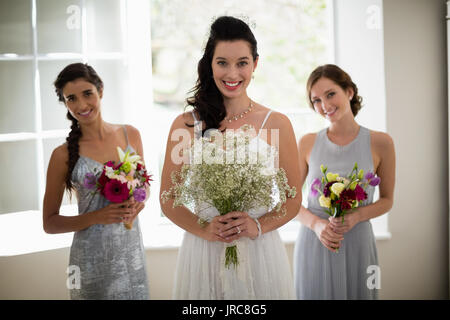 Ritratto di sposa e le sue damigelle hanno piedi con bouquet a casa Foto Stock