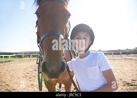 Rider la ragazza in piedi con un cavallo al ranch in una giornata di sole Foto Stock