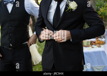 Sezione intermedia dello sposo abbottonatura una tuta di nozze Foto Stock