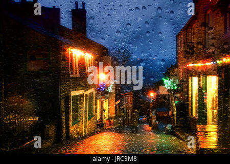Guardando attraverso una finestra Misty con gocce di pioggia a Main Street Haworth West Yorkshire al tempo di Natale Foto Stock