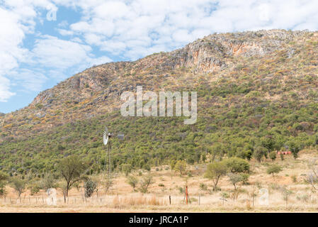 Un mulino a vento che acqua-pompa con uno sfondo montano accanto alla B8-strada tra Otavi e Kombat nella regione di Otjozondjupa di Namibia Foto Stock