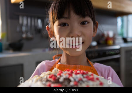 Close-up ritratto della ragazza con la torta nella cucina di casa Foto Stock