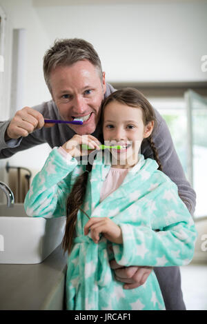 Ritratto di sorridere padre e figlia spazzolare i denti in bagno a casa Foto Stock