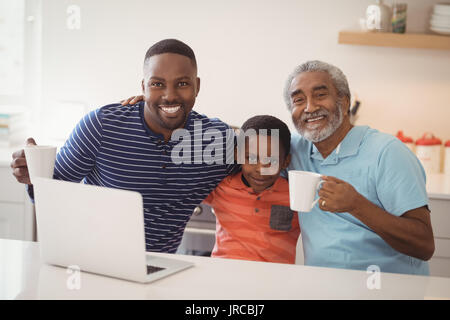 Ritratto di felice multi-generazione famiglia avente tazza di caffè nella cucina di casa Foto Stock