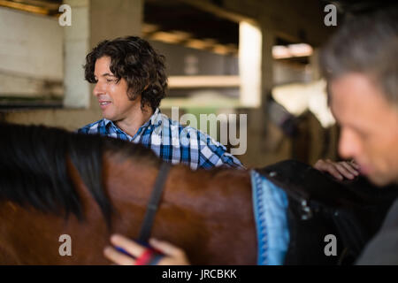 Close-up di uomo governare il cavallo nella stalla Foto Stock